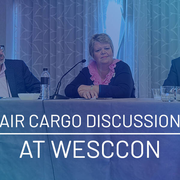 Three people are seated at a table labeled "Air Cargo Discussion at WESCCON" engaging in a panel discussion. Microphones and water bottles are on the table, while a patterned curtain serves as the backdrop, adding an elegant touch to this insightful exchange on air cargo topics.