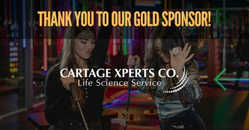 Two women are playing mini-golf indoors, holding putters. One woman is spinning a golf ball in the air. The image highlights: "Thank you to our Gold Sponsor!" and "Cartage Xperts Co. Life Science Service," a proud member of the Air Cargo Association in Chicago.